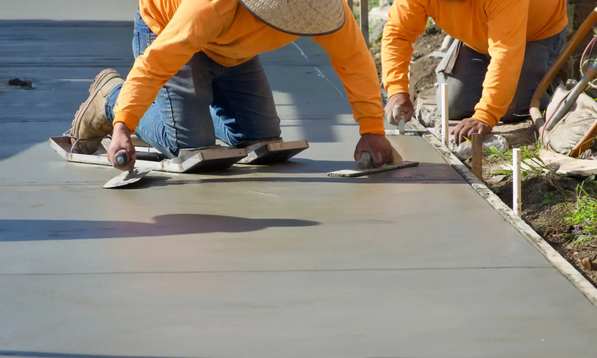 Workers leveling concrete surface outdoors
